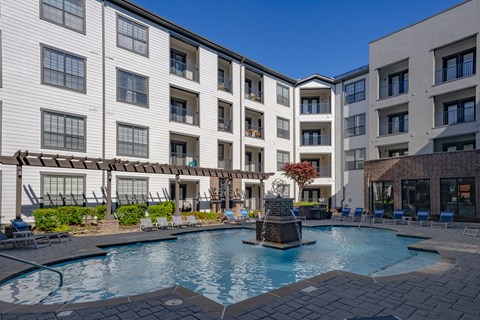 an outdoor pool with a fountain in front of a white building